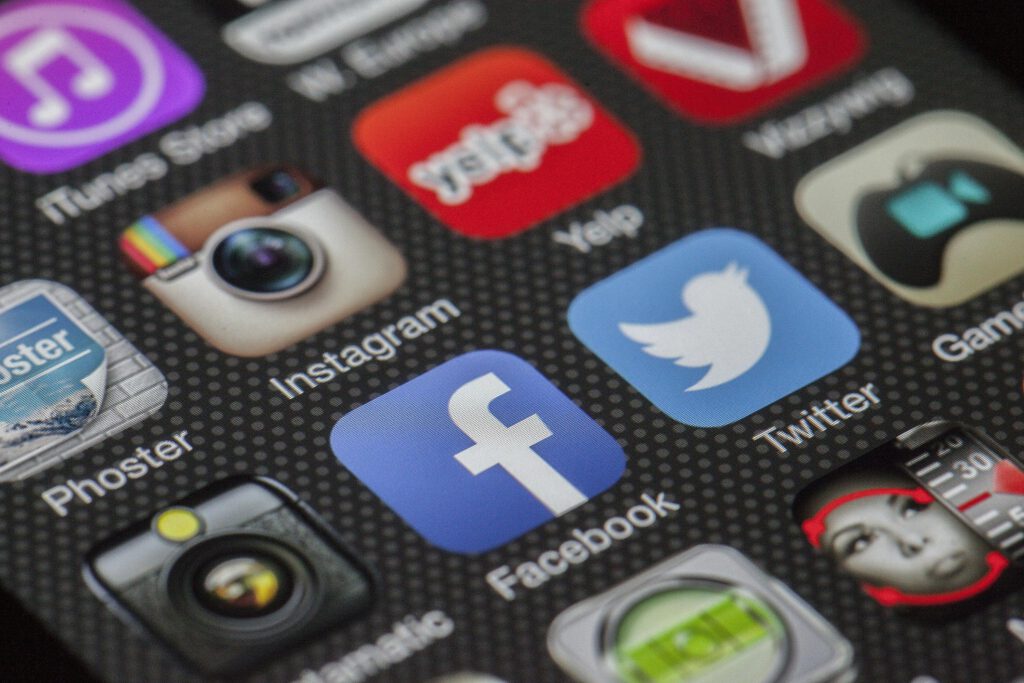 Verschiedene Apps auf einem Smartphone darunter Facebook, X (ehemals Twitter), Instagram, Phoster, Yelp und andere die unscharf sind