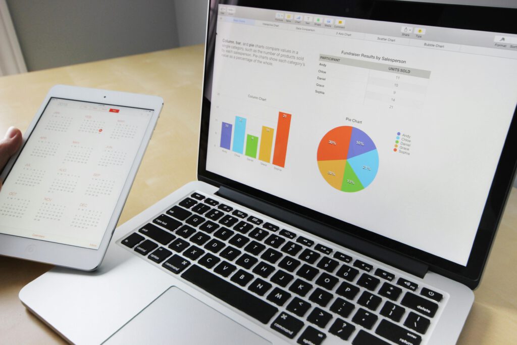 Laptop mit angeschaltetem Display, das ein Diagramm zeigt, daneben ein Tablet, das einen Kalender zeigt